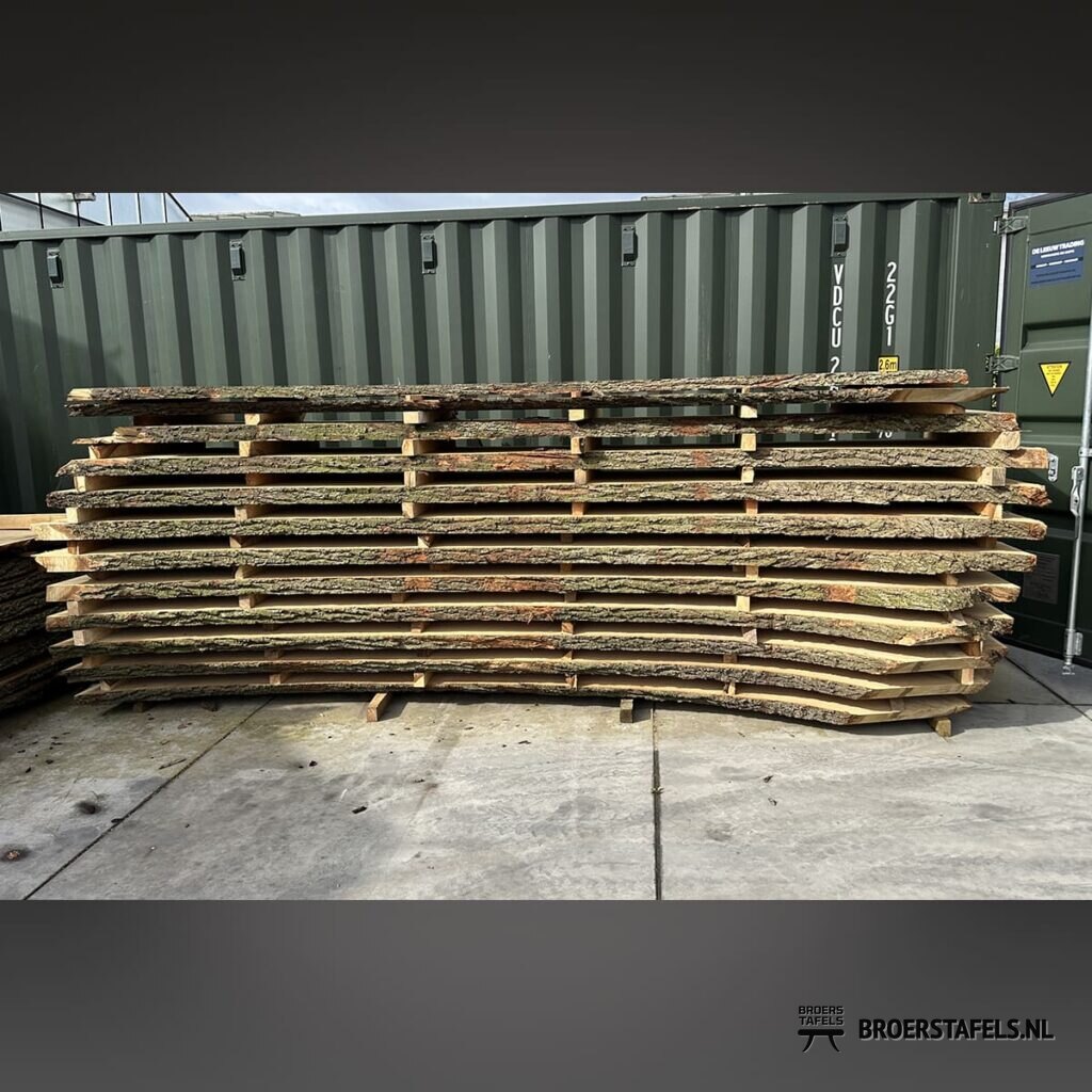 Stapel massief eikenhouten tafelbladen in het atelier
